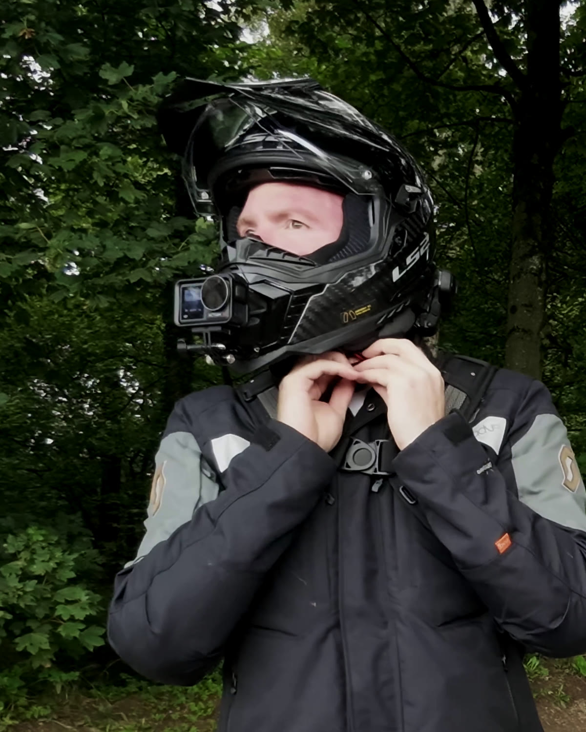 A rider fastening a helmet with a camera mounted on the chin bar
